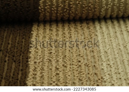 Extreme closeup of rolled up gradient brown rug with thick fiber