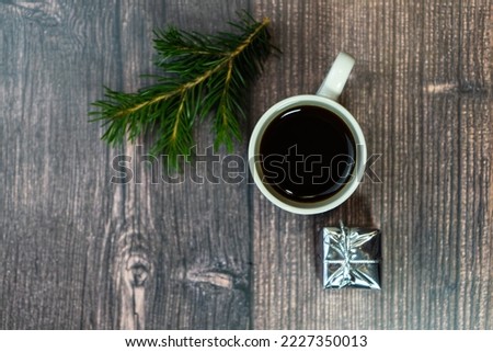 Wooden table with a cup of coffee and a Christmas decoration in a gift box. The concept of celebrating Christmas and New Year. Top view with copy space, flat layout. Selective focus.