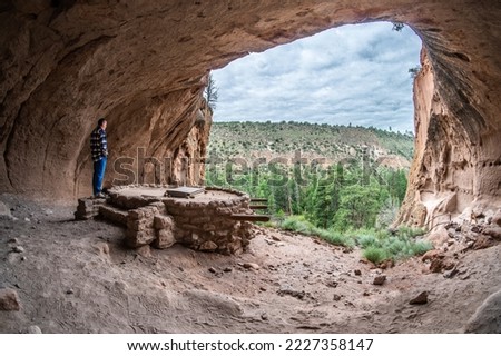 Mature caucasian man looking watching a kiva built, reconstructed in a rock dwelling area, Alcove House, Bandelier National Monument, New Mexico Royalty-Free Stock Photo #2227358147