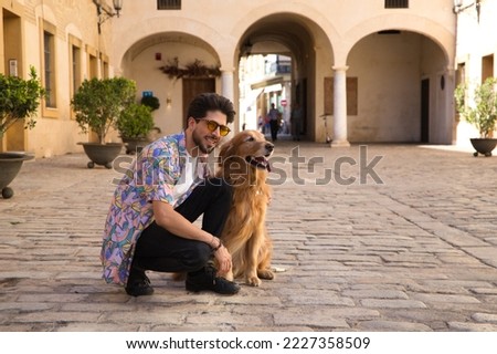 young handsome Hispanic man with his brown golden retriever dog, they are crouched down looking at the same place. Concept pets, animals, dogs, pet love, golden retriever.