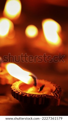 Close up shot of Dev Deepawali 2022 festival, Earthen lamps lit on the stairs leading to the Ganges with selective focus. Thousands of diyas (oil lamps) are lined up on the stairs near Ganges.