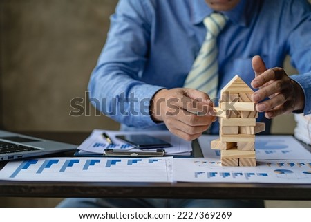 Businessman working with showing business graph Business expansion and growth plan With wooden block tower next to it with direction of growth and success, property and real estate insurance concept