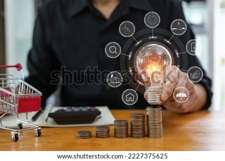Business man holding light bulb on the Green background nature and writing on note book it for financial