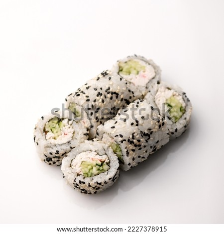 Sushi roll California in sesame with crab meat. Filled with crab meat, avocado and cucumber, wrapped in nori seaweed and rice with black and white sesame seeds. Japanese cuisine. white background.