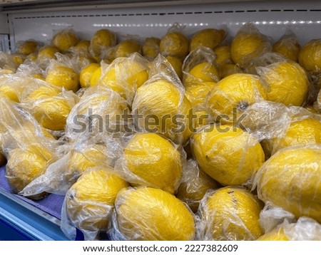 lemons that have been wrapped in plastic that are sold in a modern fruit shop