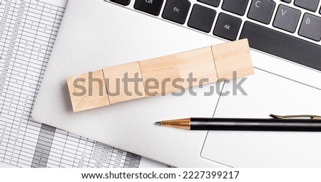 Five empty wooden cubes in a row on a computer keyboard next to a pen. Free text and for business template.