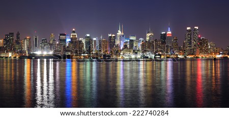 New York City Manhattan midtown skyline at night with lights reflection over Hudson River viewed from New Jersey Weehawken waterfront.