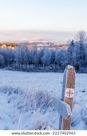 Frosty sign on a wooden pole for a pilgrims path