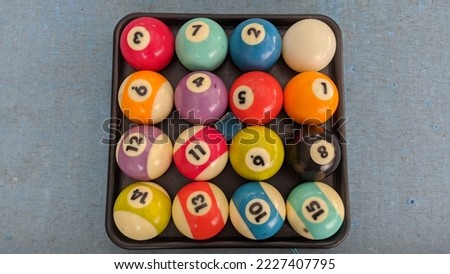 A collection of 15 billiard balls arranged in an irregular order. Including white balls. The ball is on the pool table. There are defects around the ball due to play.