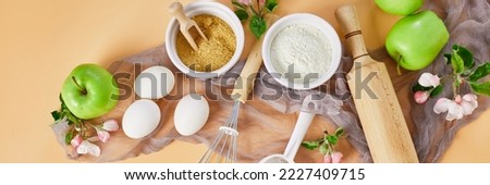 Banner Bakery  or cooking frame with flower and apples, ingredients, kitchen items for pastry on pastel orange background,  spring cooking theme. Top view, copy space. Royalty-Free Stock Photo #2227409715