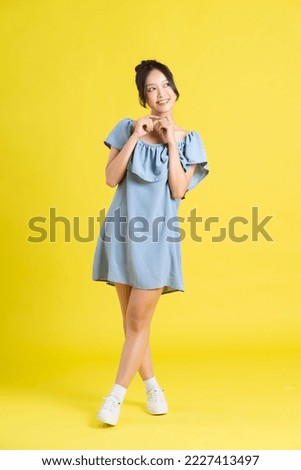 portrait of Asian woman in skirt posing on yellow background