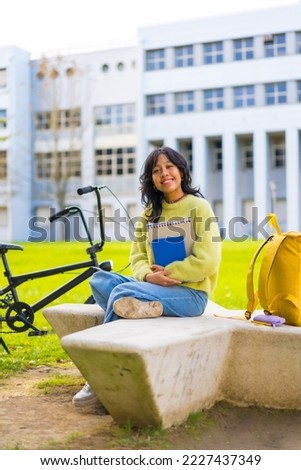 An asian female student smiling sitting in the university campus in the break from classes