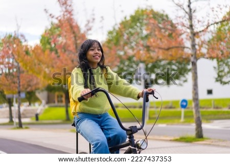 Young asian female student with backpack cycling on her way to college in autumn, healthy life, eco friendly