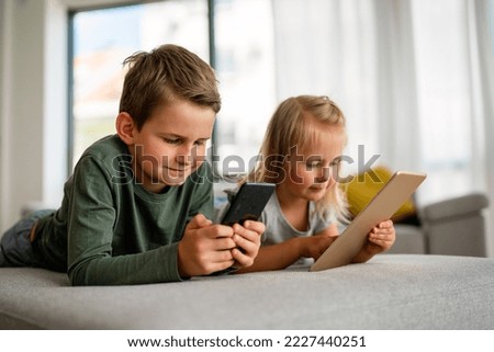 Little kids holding smartphone, tablet playing mobile game online, child and gadget concept