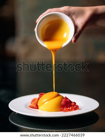 Mango coulis pouring over vanilla custard, delicious strawberry caviar. Molecular cuisine in fancy restaurant Royalty-Free Stock Photo #2227466039