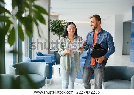 Two business coworkers walking through a lobby of an office building. Royalty-Free Stock Photo #2227472255