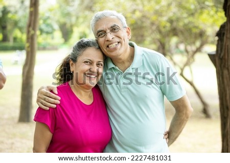Portrait of Happy indian senior couple at summer park. Old Asian man and woman standing outdoor smiling. elderly people retirement life, Health and fitness. Relations and bonding. Stress free. 
