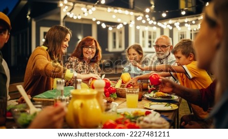 Group of Multiethnic Diverse People Having Fun, Communicating with Each Other and Eating at Outdoors Dinner. Family and Friends Gathered Outside Their Home on a Warm Summer Evening. Royalty-Free Stock Photo #2227481211