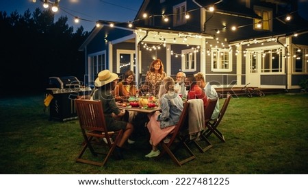 Parents, Children and Friends Gathered at a Barbecue Dinner Table Outside a Beautiful Home with Lights Decorations. Old and Young People Have Fun and Eat Meals. Garden Party Celebration in a Backyard. Royalty-Free Stock Photo #2227481225