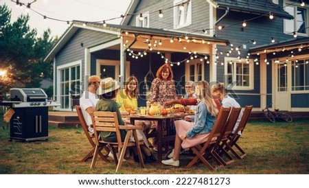 Parents, Children and Friends Gathered at a Barbecue Dinner Table Outside a Beautiful Home. Multicultural Old and Young People Have Fun, Eat and Drink. Garden Party Celebration in a Backyard.