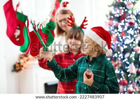 Kids opening Christmas presents. Child searching for candy and gifts in stocking advent calendar on winter morning. Decorated Christmas tree for family with children. Xmas fun.