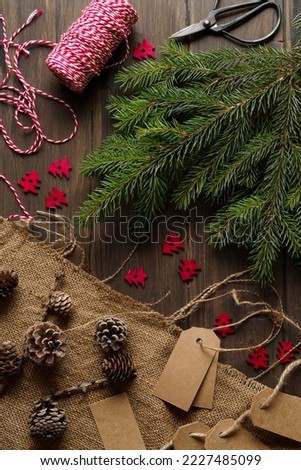 Christmas decorations: fir branches, ribbon, label, pine cone, on wooden background. 