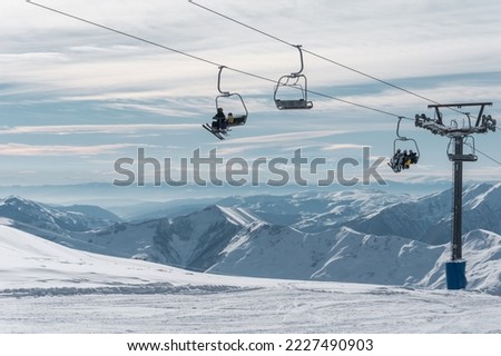 skiers and snowboarders on ski lift at winter at resort Royalty-Free Stock Photo #2227490903