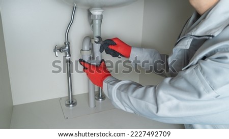 A worker repairing the drain pipe of the washbasin.