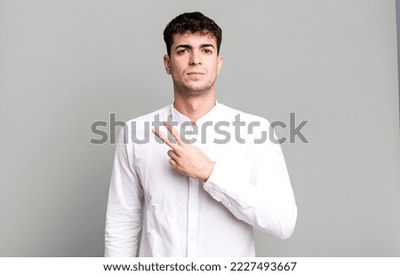 feeling happy, positive and successful, with hand making v shape over chest, showing victory or peace Royalty-Free Stock Photo #2227493667