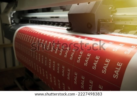 Sublimation printing of stickers on a printed printer. Printing flyers for sale in a hypermarket..Large-format printing in production. Royalty-Free Stock Photo #2227498383