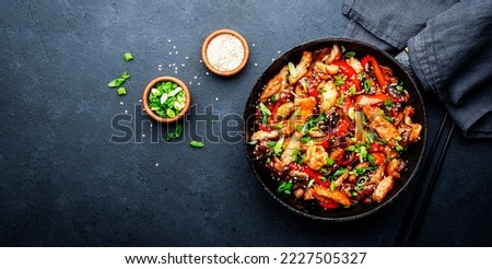 Stir fry with turkey fillet, paprika, mushrooms, green chives and sesame seeds in frying pan. Asian cuisine dish. Black stone kitchen table background, top view Royalty-Free Stock Photo #2227505327