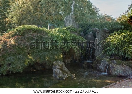 Scenic Japanese style gardens with a waterfall in the park of Bietigheim-Bissingen, Baden-Wuerttemberg, Germany, Europe. Japanese water garden. Waterfall with trees in Japanese green Garden Park green