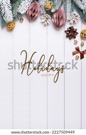 Happy holidays text on vertical wooden background with flat lay snow pine trees, paper Christmas balls.