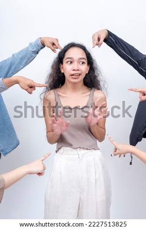 A shocked young woman in disbelief being blamed. Arms from anonymous people pointing at her. Accusation and trial concept. Court of public opinion. Royalty-Free Stock Photo #2227513825