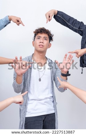 A young man pleads his innocence from bashers cornering and pointing at him. Accusation and trial concept. Court of public opinion. Royalty-Free Stock Photo #2227513887