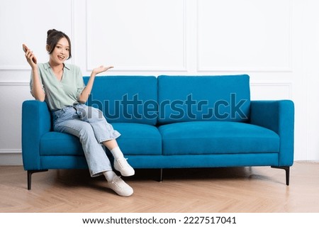 image of young asian girl sitting on sofa at home Royalty-Free Stock Photo #2227517041