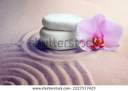 Stack of white stones and beautiful flower on sand with pattern. Zen, meditation, harmony