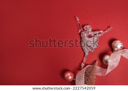 Decoration for Christmas, a small figurine of a ballerina with pink balls on red background, greeting card with copy space