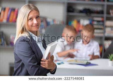 Smiling woman teacher with laptop in school background