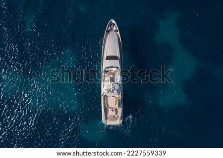 A large Mega yacht for travel is anchored on clear water, top view. Innovative large yachts on the water vice air. Royalty-Free Stock Photo #2227559339