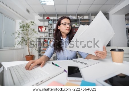 Young woman sitting at table and working with business paper