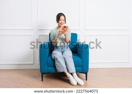 image of young Asian girl sitting on sofa at home Royalty-Free Stock Photo #2227564073