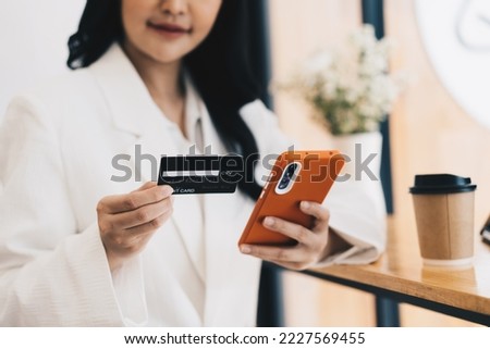 Young woman holding credit card and using laptop computer.