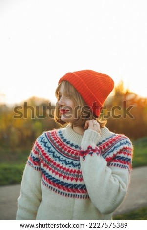 Bright winter portrait of a beautiful young woman in a knitted red hat against the background of Christmas trees. Eco christmas, winter holidays.