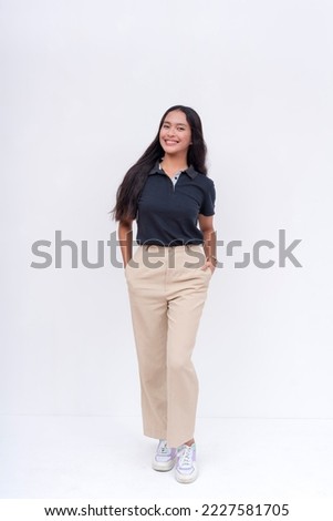 A lovely Filipina intern in a black polo shirt and khaki pants. Isolated on a white background, full body photo.