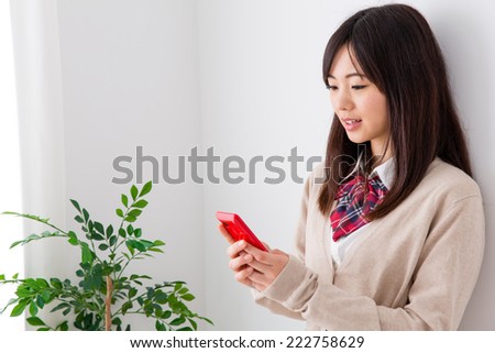 young asian student using smart phone in the white room 