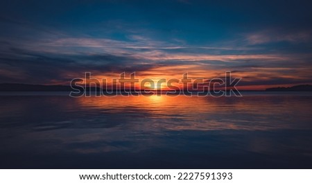 A panoramic view of the afterlife on a beautiful sunset with strong colors on a mirror-smooth lake in midsummer. Beautiful sight. Royalty-Free Stock Photo #2227591393