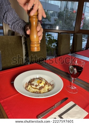 Spaghetti with ribs and eggs served on a white porcelain plate, served on a wooden and red table, with a glass of wine next to it. Great Macro Detail Shot Conceptual Food Shot International Cuisine It