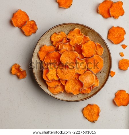 Healthy organic sweet potato chips in a bowl on a stone background. Vegetarian and vegan appetizer. Diet. A useful snack. Selective focus, top view, square picture