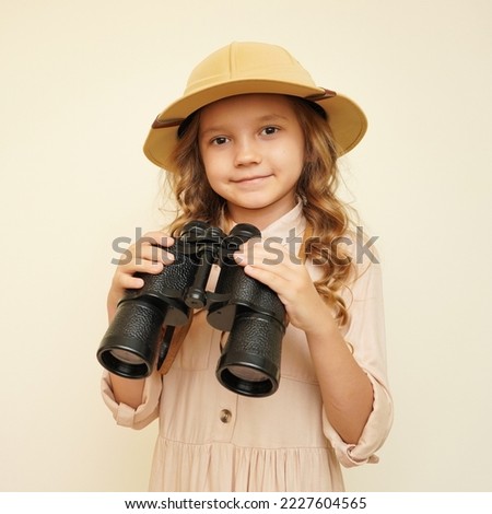 Traveler child. Child discoverer. Young researcher. Little girl in a safari hat with binoculars in her hands. Concept: search for adventure and treasure. Cute happy girl in safari clothes Royalty-Free Stock Photo #2227604565